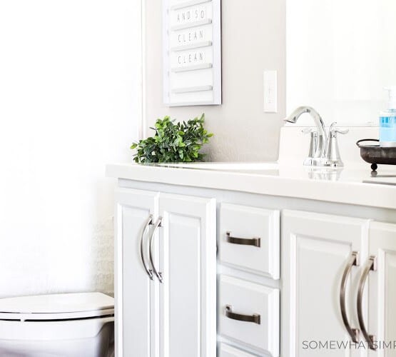 a kids bathroom that has white cabinets with nickle hardware