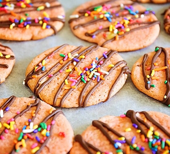 banana cookies topped with drizzled chocolate and colorful sprinkles