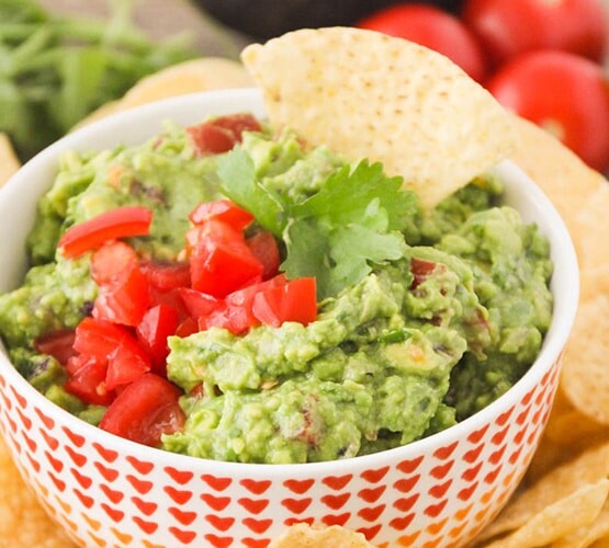 a bowl of Zesty Guacamole next to a pile of tortilla chips