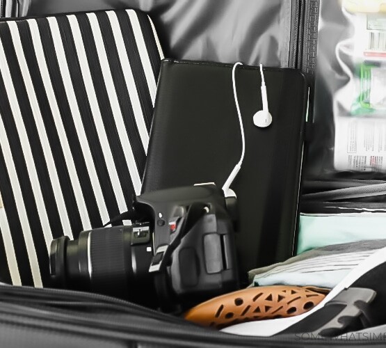 packing tips a camera, a tablet and a laptop case sitting on top of an open suitcase