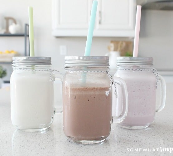 Chocolate, strawberry and vanilla Slim Fast shakes in mason jar glasses on a counter and each have a pastel colored straw