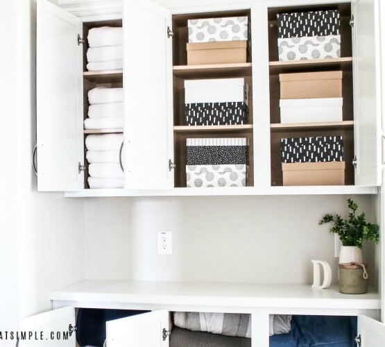 the doors of an organized white linen closet that are open revealing neatly stacked boxes and folded blankets