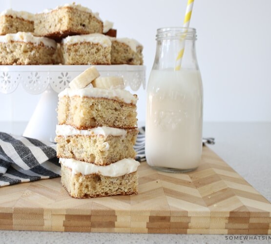 a stack of banana bars topped with cream cheese frosting and sliced bananas