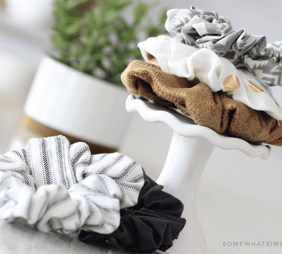 the DIY hair scrunchies stacked on top of each other on a small stand with two more scrunchies lying next to the stand on a counter