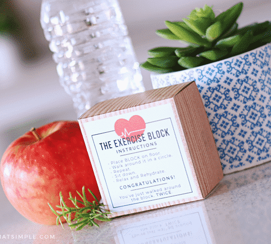 an exercise block with a funny printable on the outside sitting on a counter next to a bottle of water and an apple