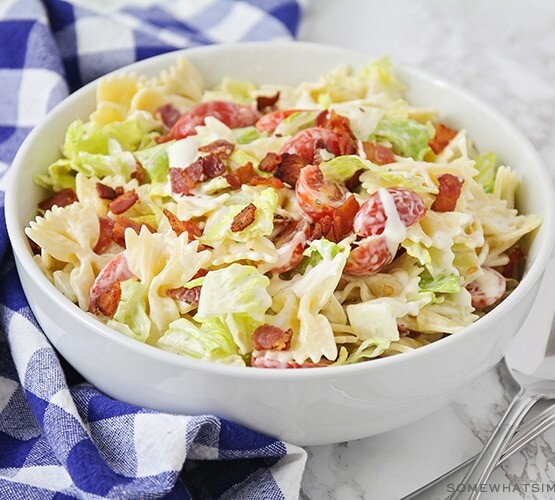 a white bowl of bow tie BLT pasta salad with lettuce, bacon and tomatoes.