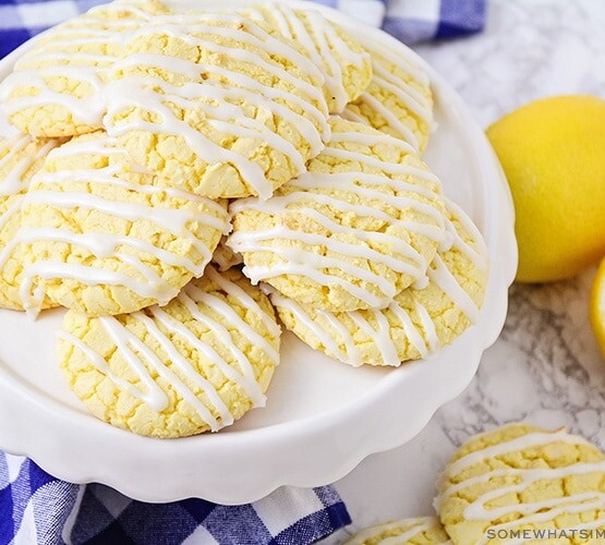 a stack of lemon cookies made from a box of cake mix with white frosting drizzled over the op