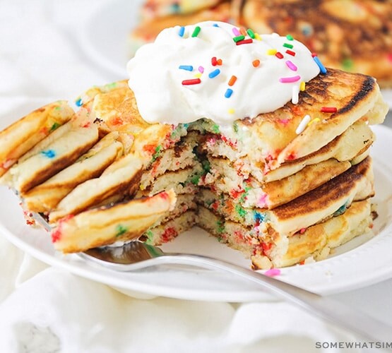 a stack of cake mix pancakes topped with whipped cream and sprinkles