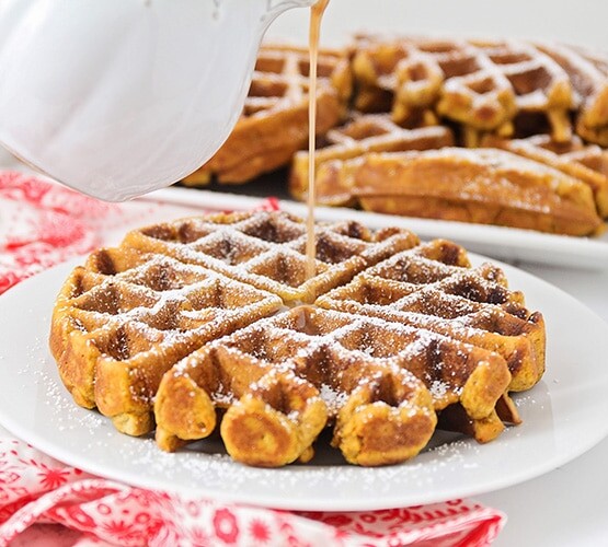 cinnamon syrup being poured over gingerbread waffles