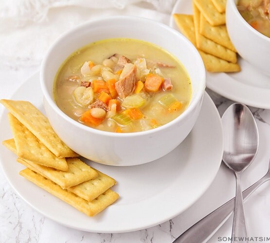 A bowl of soup filled with ham, white beans and vegetables