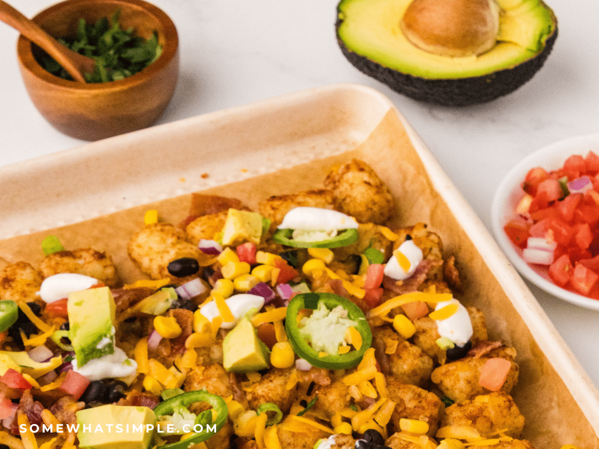 close up of a tray of Tatchos with avocado and other fresh toppings around the tray